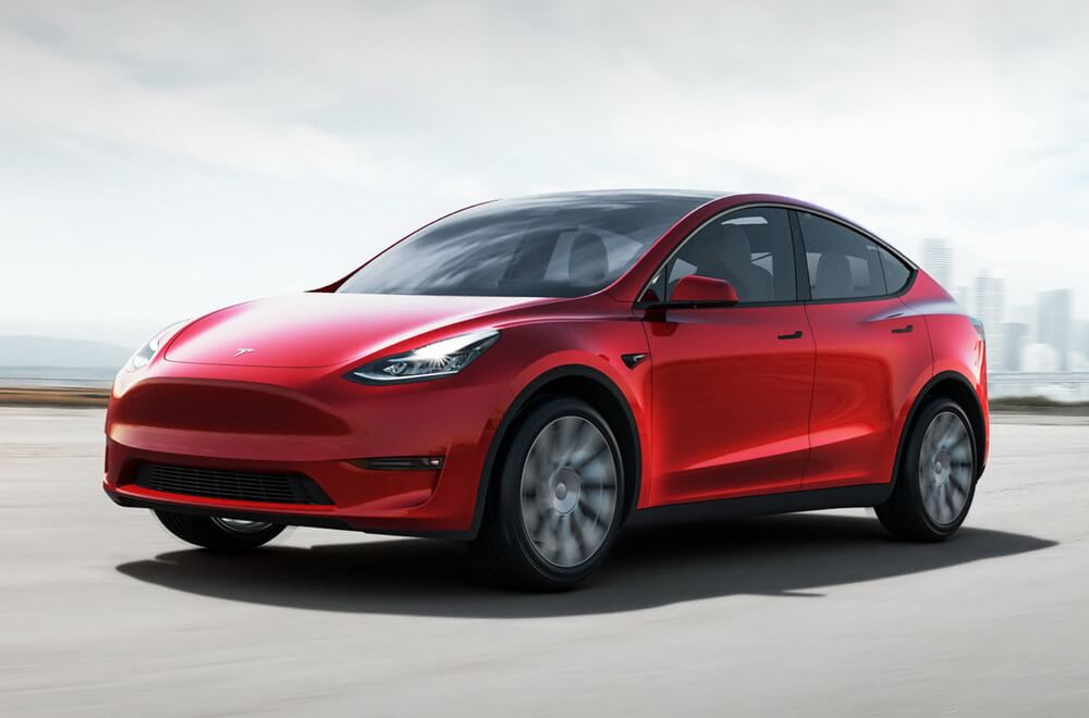 Біла Tesla Model Y на міській вулиці Києва, панорамний дах і LED-оптика, ранкове світло.